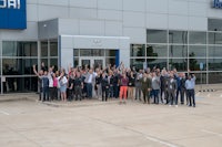 a group of people posing in front of a hyundai dealership